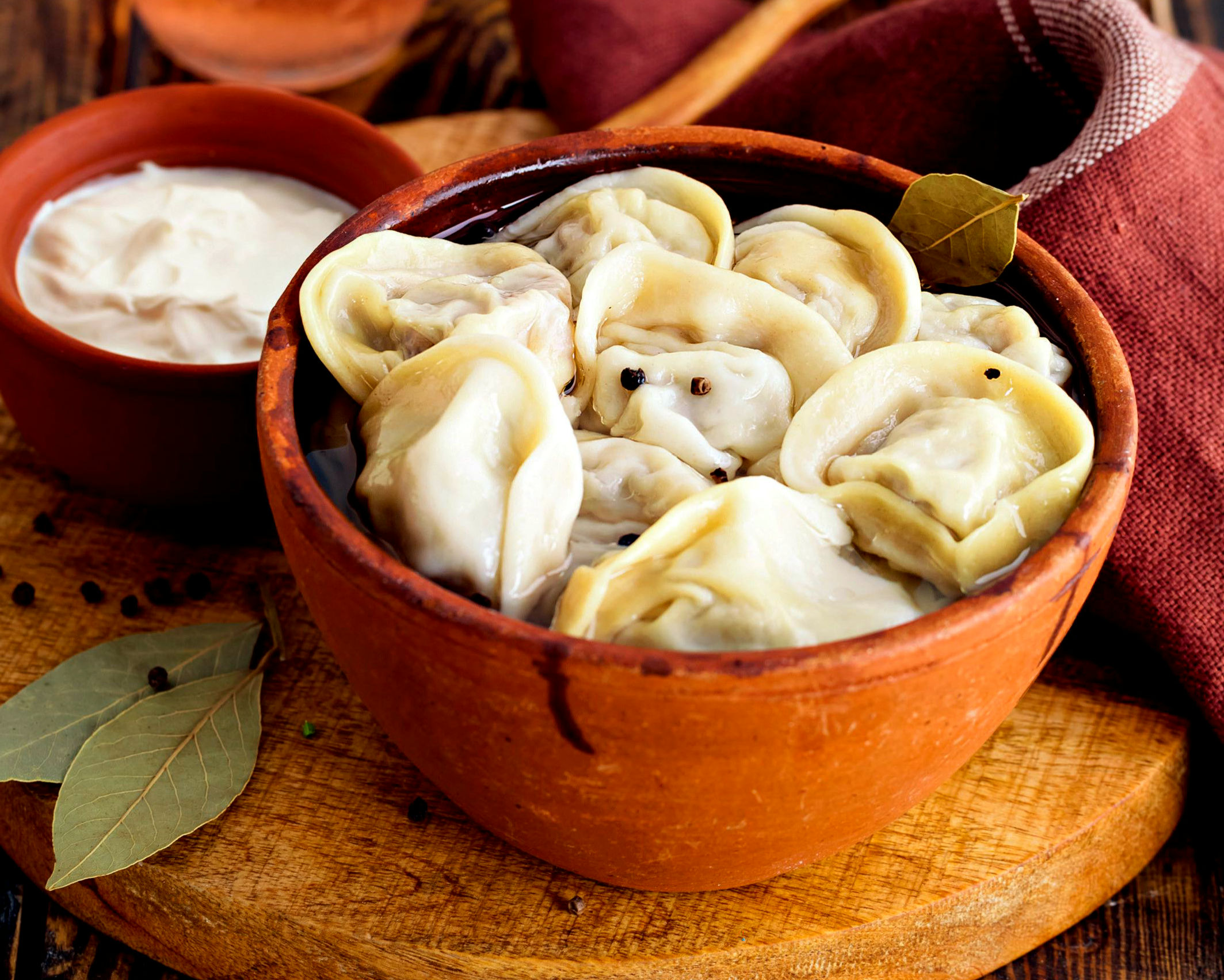 Пельмени по-деревенски с бульоном, сливочным маслом, сметаной и зеленью в горшочке Пельмени по-деревенски с бульоном, сливочным маслом, сметаной и зеленью в горшочке